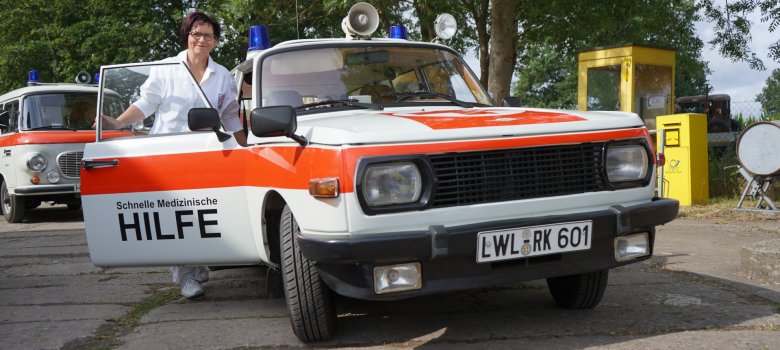 Woman standing by a vintage ambulance on the grounds of the Beuster Blue Light Museum