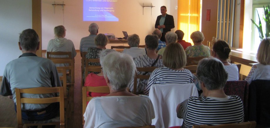 Dr. Dr. med. Daniel Kügler, Chefarzt der Klinik für Innere Medizin und Internistische Intensivmedizin hält den Fachvortrag ab Besucher vor Leinwand während des Fachvortrages durch den Dr. Dr. med. Daniel Kügler, Chefarzt der Klinik für Innere Medizin und Internistische Intensivmedizin